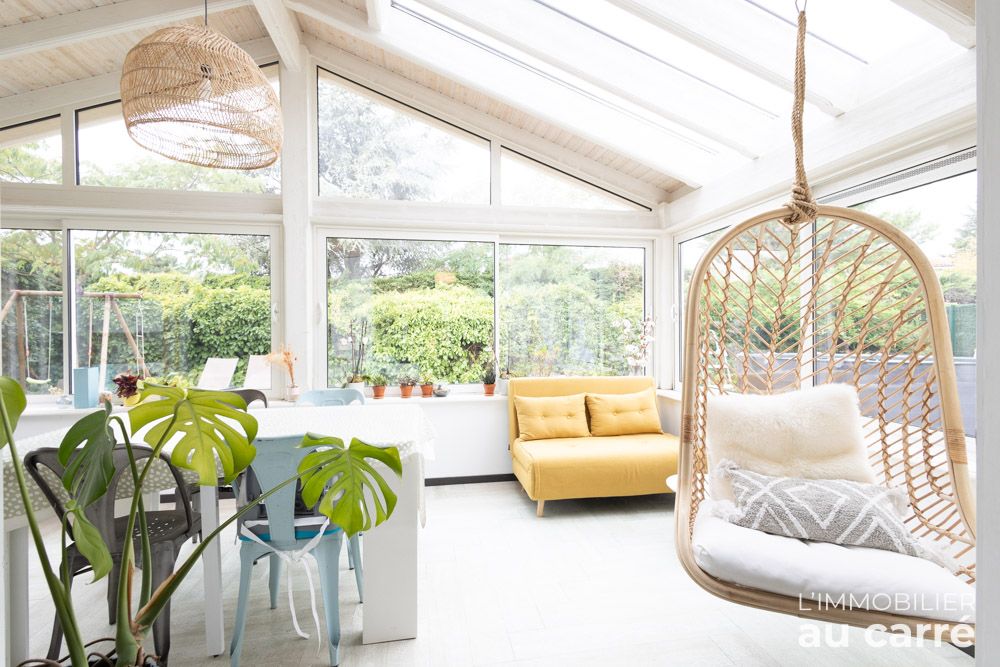 Véranda avec fauteuil suspendu et vue sur le jardin